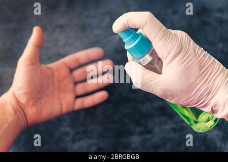 Pulizia delle mani da batteri e microbi con alcool spray, prevenzione di coronavirus e altre malattie Foto Stock