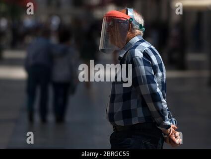 21 maggio 2020, Malaga, Spagna: Un uomo anziano che cammina lungo la strada indossando uno scudo facciale come precauzione, durante un blocco parziale nazionale.la Spagna sta attraversando un piano di riduzione verso una ''nuova normalità'', con misure rilassanti che sono scaturite dall'epidemia di COVID-19. La sua fase 1 ora che permette alle persone di visitare le loro famiglie non oltre un massimo di 10 persone, riapertura di chiese, imprese, negozi e bar/ristoranti con le loro terrazze limitate al 50% e mantenendo una distanza di sicurezza con l'uso di maschere facciali. (Credit Image: © Jesus Merida/SOPA immagini via ZUMA Wire Foto Stock