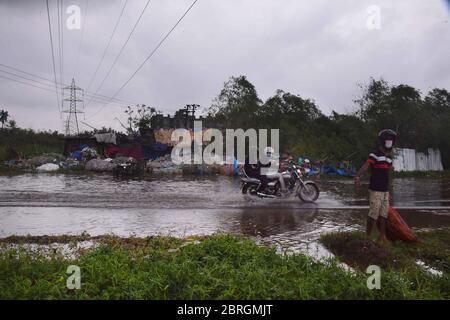 Kolkata. 21 Maggio 2020. I pendolari attraversano una strada costellata d'acqua dopo la violenta tempesta ciclonica Amphan, che ha colpito Kolkata, India, il 21 maggio 2020. Il ministro capo dello stato orientale dell'India del Bengala occidentale, Mamata Banerjee, ha detto giovedì che 72 persone sono state uccise nel suo stato a causa della grave tempesta ciclonica Amphan. La tempesta ciclonica che ha innescato venti raffazzonati fino a 190 km/h e pioggia ha colpito il Bengala occidentale e Odisha costiera il mercoledì sera, appiattendo case di fortuna e sradicare pali elettrici e alberi. Credit: Sr/Xinhua/Alamy Live News Foto Stock