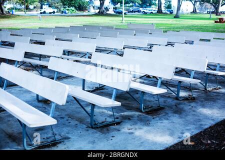 file di panchine bianche vuote in un parco pubblico Foto Stock