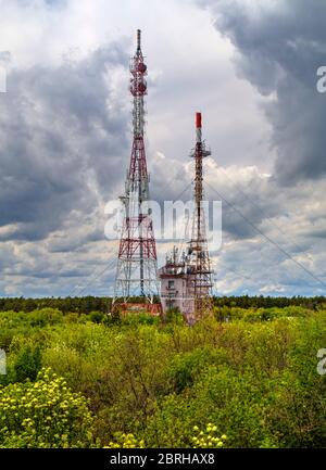 Splendido paesaggio con cielo suggestivo e torri d'antenna in una foresta verde fresca Foto Stock