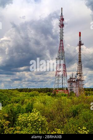 Splendido paesaggio con cielo suggestivo e torri d'antenna in una foresta verde fresca Foto Stock