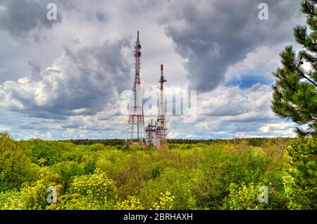 Splendido paesaggio con cielo suggestivo e torri d'antenna in una foresta verde fresca Foto Stock