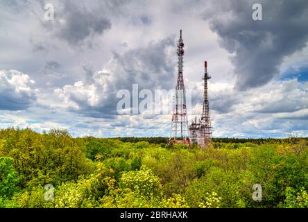 Splendido paesaggio con cielo suggestivo e torri d'antenna in una foresta verde fresca Foto Stock