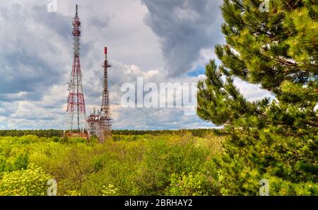 Splendido paesaggio con cielo suggestivo e torri d'antenna in una foresta verde fresca Foto Stock