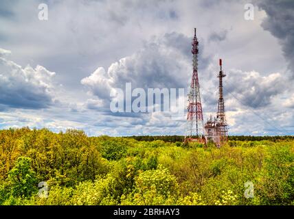 Splendido paesaggio con cielo suggestivo e torri d'antenna in una foresta verde fresca Foto Stock