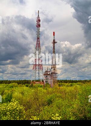 Splendido paesaggio con cielo suggestivo e torri d'antenna in una foresta verde fresca Foto Stock