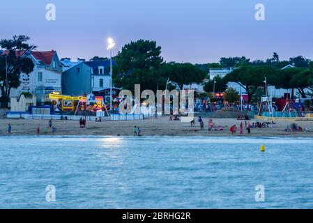 Saint-Palais-sur-Mer, Francia: La spiaggia Plage du Bureau nel centro della città con ristoranti, alberghi e negozi in background, al tramonto. Foto Stock