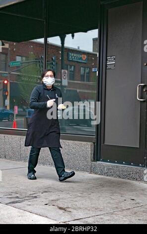 Cameriere mascherato che prende ordini al ristorante Cafe latte per il prelievo sul marciapiede durante la pandemia COVID-19 mantenendo una distanza sociale. St Paul Minnesota, Minnesota, Stati Uniti Foto Stock