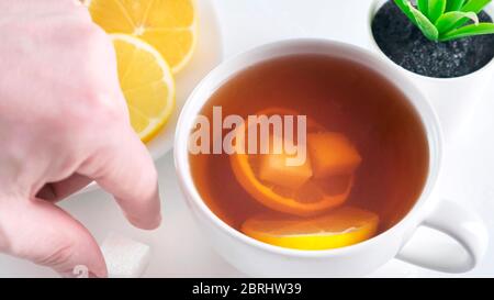 Aggiungere lo zucchero alla tazza di tè del whute sul tavolo della cucina. Primo piano. Foto Stock