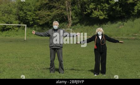 Coppia attiva anziana anziana 80 anni. L'uomo e la donna caucasici fanno mattina esercizi fisici stretching in campo sportivo. Fitness famiglia tempo libero. Stile di vita sano in quarantena coronavirus Foto Stock