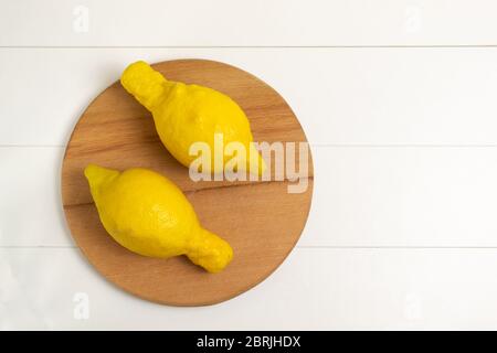 Limoni brutto su un tagliere di legno su sfondo bianco. Vista dall'alto. Orientamento orizzontale. Il concetto di brutto verdura e frutta. Foto Stock