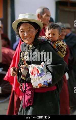 Donna che porta un bambino sulla schiena, Xiahe, Prefettura autonoma tibetana di Gannan, Gansu, Cina Foto Stock