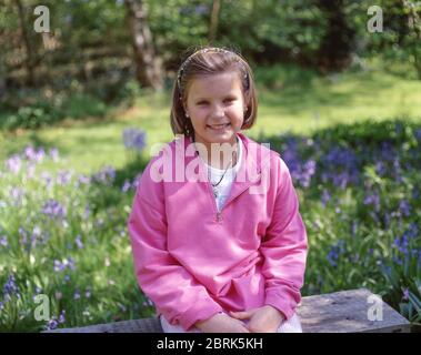 Giovane ragazza seduta in giardino, Ascot, Berkshire, Inghilterra, Regno Unito Foto Stock