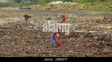 Inquinamento marino: Garbage oggetto di dumping in Sri Lanka mare nei pressi di Colombo. donne raccoglie le cose di plastica in un mucchio di rifiuti portati dal surf dal mare Foto Stock
