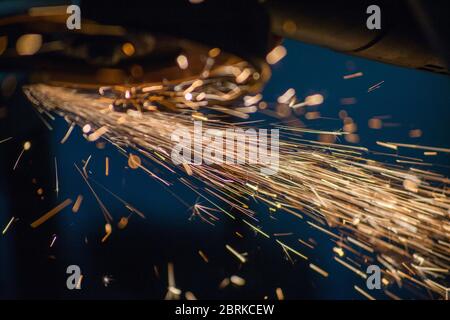 scintille volanti di metallo macinato, lavorare con una smerigliatrice manuale, Foto Stock