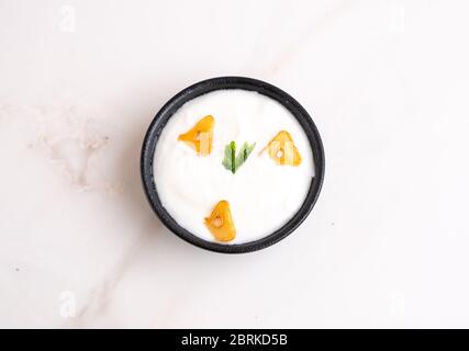 Salsa all'aglio in una ciotola su fondo bianco con qualche spicchio di aglio condito. Foto Stock
