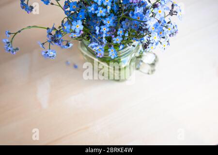 bouquet di fiori "forget-me-not" in una tazza di vetro su uno sfondo non focalizzato Foto Stock