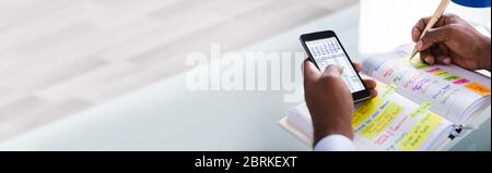 Pianificazione di eventi e attività utilizzando Calendario e smartphone. Uomo africano Foto Stock