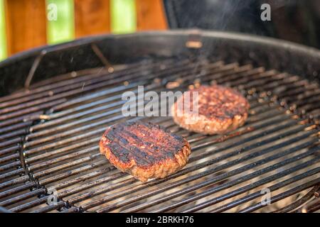 carne alla griglia - due hamburger bruciati su una griglia all'aperto Foto Stock