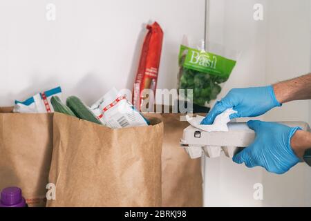 COVID-19: È necessario pulire i vostri generi alimentari consegnati a casa. Uomo in quarantena strofinare cartone con salviette igienizzanti dopo l'acquisto o la ricezione di sacchetti di consegna online. Foto Stock