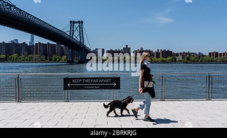 New York, New York, Stati Uniti. 21 Maggio 2020. New York, New York, Stati Uniti: Una donna porta il suo cane per una passeggiata al Domino Park a Brooklyn e un cartello ricorda ai visitatori di garantire la distanza sociale durante l'epidemia di Coronavirus. Credit: Corine Sciboz/ZUMA Wire/Alamy Live News Foto Stock