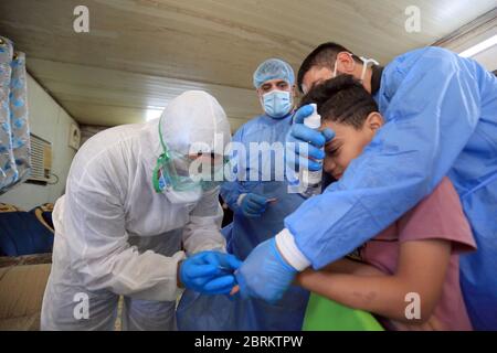 Baghdad, Iraq. 21 Maggio 2020. Un medico prende un campione da un ragazzo per il test COVID-19 nel distretto di Sadr City a Baghdad, Iraq, il 21 maggio 2020. Il Ministero della Salute iracheno di giovedì ha registrato 153 nuovi casi di COVID-19, il più alto aumento giornaliero finora, portando il numero totale di infezioni a 3,877 nel paese. Credit: Khalil Dawood/Xinhua/Alamy Live News Foto Stock