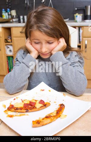 Kind vor Teller mit Pizzaresten, MR: Sì Foto Stock