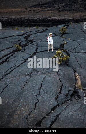 Una donna si trova sulla lava crackizzata del pavimento del cratere Kilauea Iki, Hawaii Volcanoes National Park, Hawai'i, USA Foto Stock