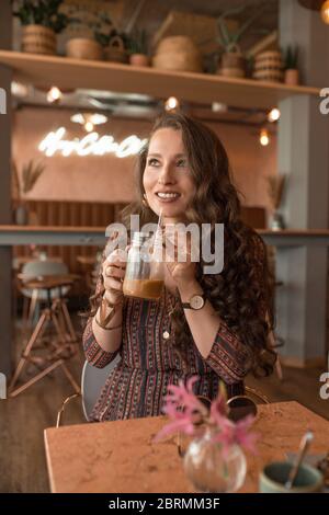 Giovane bella donna che si gode il suo caffè presso la caffetteria Foto Stock