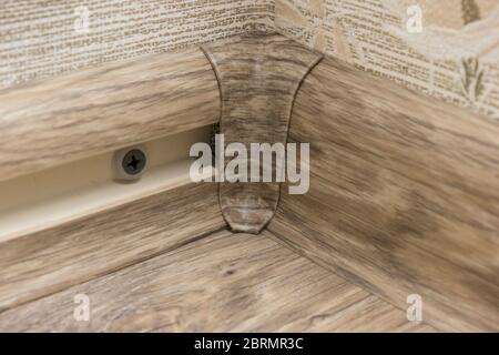 Installazione di un battitcopa in plastica sull'angolo interno del pavimento. Riparazione in casa Foto Stock