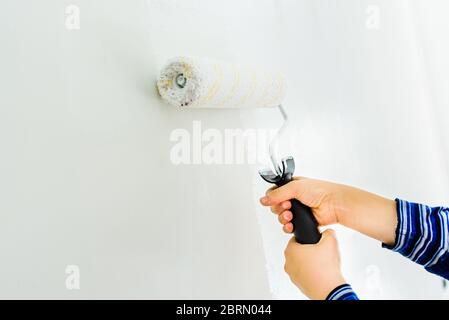 Ragazzo aiuta la sua famiglia a dipingere un muro bianco. Foto Stock