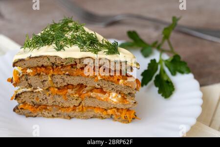 torta di fegato in un piatto su un tavolo di legno. Snack da pancake al fegato e verdure Foto Stock