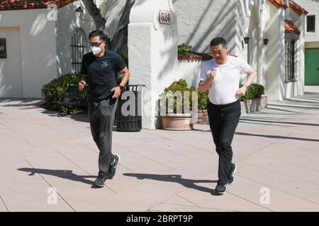 San Gabriel, California, Stati Uniti. 20 Maggio 2020. Lo sprinter olimpico Feng li e l'host televisivo Joey Zhou fanno una corsa di addestramento davanti alla San Gabriel Mission Playhouse come parte del 'Pandemic Fitness Program' di Joey Zhou per aiutare gli altri a fare esercizio mentre rimangono al sicuro durante la pandemia Covid-19 a San Gabriel, California. Feng li ha rappresentato la Cina ai Giochi Olimpici estivi del 1988 e ora vive negli Stati Uniti. Il San Gabriel Mission Playhouse è stato costruito nel 1927 ed è un luogo storico per le arti dello spettacolo. Credito: Sheri Determan Foto Stock