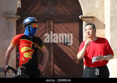 San Gabriel, California, Stati Uniti. 20 Maggio 2020. L'ospite della TV Joey Zhou intervista Drew Hodis della squadra ciclistica dell'Università della California del Sud (USC) alla missione di San Gabriel come parte del 'programma di idoneità pandemico' di Joey Zhou per aiutare gli altri a ottenere l'esercitazione mentre rimangono sicuri durante la pandemia di Covid-19 a San Gabriel, California. La missione di San Gabriel è stata costruita nel 1771 ed è un punto di riferimento storico a Los Angeles. Credito: Sheri Determan Foto Stock