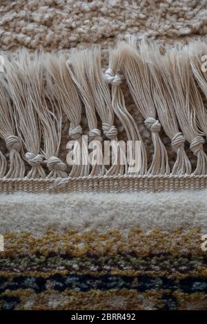 Primo piano di una sezione di una frangia di cotone su un vecchio tappeto di lana; fringe è stato annodato a mano, nodi a livelli variabili, come visto da sopra il tappeto. Foto Stock