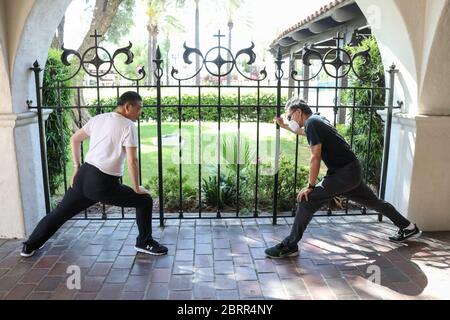 San Gabriel, California, Stati Uniti. Il 20 maggio 2020, l'ospite della TV Joey Zhou è istruito dall'ex sprinter olimpico Feng li in esercizi di riscaldamento come parte del 'programma di idoneità pandemico' di Joey Zhou per aiutare gli altri ad ottenere l'esercitazione mentre si rimane sicuri durante la pandemia di Covid-19 al Playhouse di missione di San Gabriel a San Gabriel, California. Feng li ha rappresentato la Cina ai Giochi Olimpici estivi del 1988 e ora vive negli Stati Uniti. Il San Gabriel Mission Playhouse è stato costruito nel 1927 ed è un luogo storico per le arti dello spettacolo. Credito: Sheri Determan Foto Stock