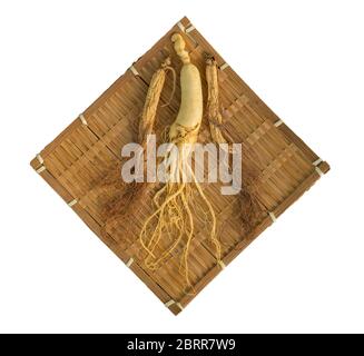 Ginseng fresco e asciutto su tessitura di bambù con stetoscopio sullo sfondo del legno. Foto Stock