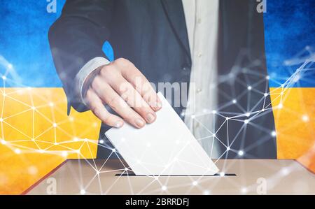 Uomo Voter mettere il voto in casella di voto sullo sfondo bandiera ucraino Foto Stock