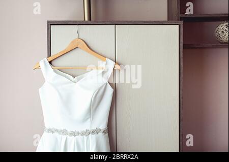 Semplice abito da sposa bianco sul rack dell'armadio Foto Stock