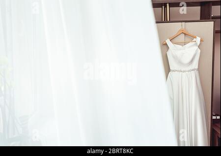 Semplice abito da sposa bianco sul rack dell'armadio Foto Stock