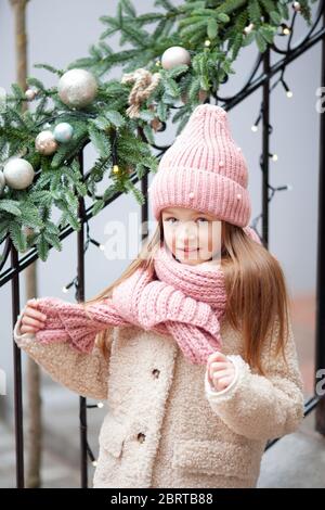 Ragazza in un cappello rosa si erge sullo sfondo di un portico decorato per Natale Foto Stock