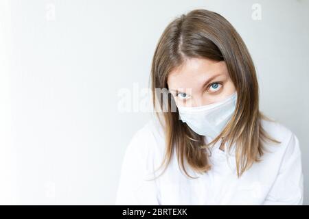 Primo piano di un'infermiera femminile che mette su una maschera per proteggere dalle malattie respiratorie dell'aria come l'influenza, il coronavirus, l'ebola, la tubercolosi, ecc Foto Stock