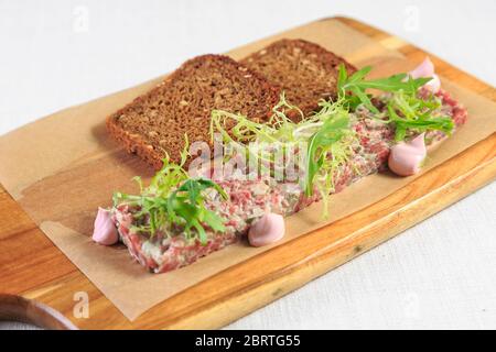 Tartare di manzo con tuorlo d'uovo su un tavolo di legno Foto Stock