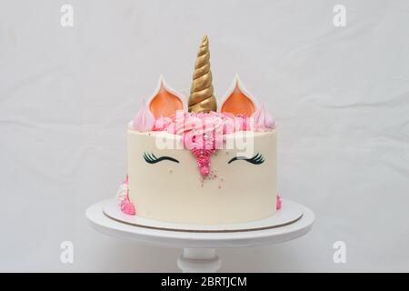 Torta a strati unicorno fatta in casa decorata con panna montata rosa. Sfondo grigio chiaro. Foto Stock