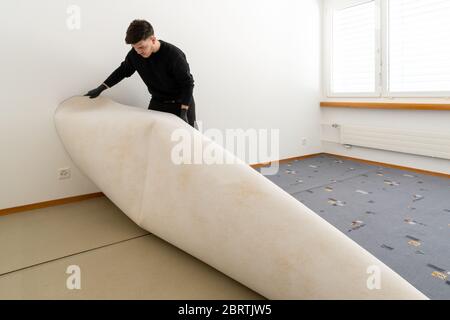 il detergente professionale di una società di gestione della struttura rimuove il tappeto vecchio brutto in una camera da letto durante i lavori di pulizia e rinovazione Foto Stock