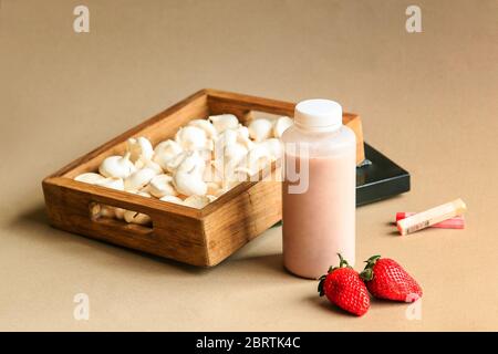 Latte di fragola in bottiglie tradizionali con cannucce su sfondo beige copyspace Foto Stock