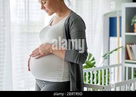 Donna incinta strobiccia il suo grande addome Foto Stock