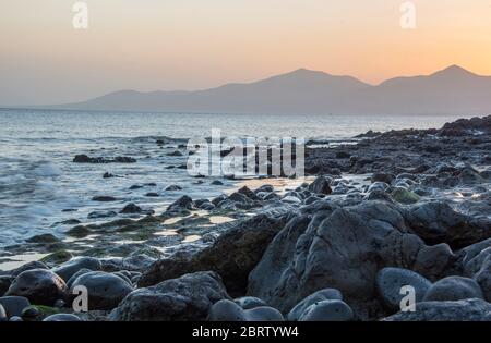 Tramonto misty sulla spiaggia di Puerto del Carmen Lanzarote, Isole Canarie Foto Stock