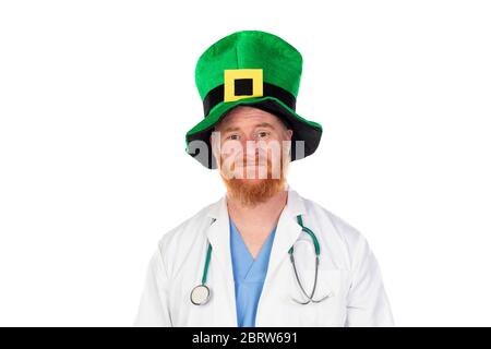 Medico di testa rossa con cappello verde guardando la macchina fotografica isolata su uno sfondo bianco Foto Stock